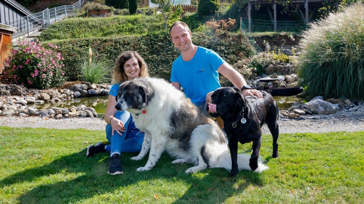 Thomas und Lisa Rehrl mit zwei Hunden im Garten des SCHNAUZERL Hotels