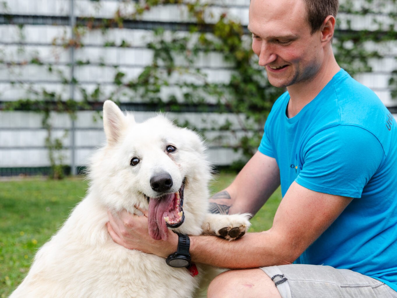 Carer cuddling a white Shepherd dog